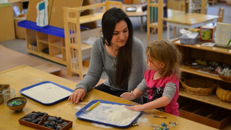 teacher and child playing with mini zen garden inside