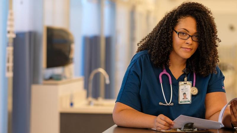 a medical assistant program student in scrubs filling out medical paperwork