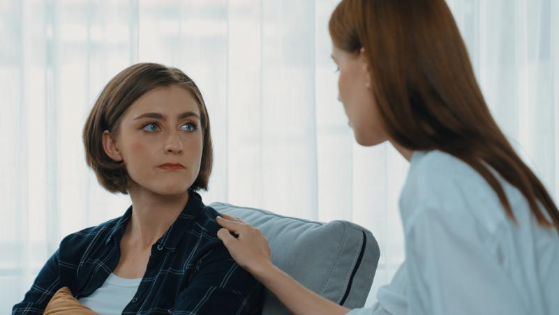 One person holding the shoulder of another as they have a discussion.