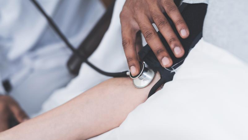 A BSN student uses a stethoscope and blood pressure cuff to measure a patient's blood pressure.