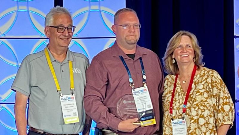 Fred Rankin receives an award at ISAC 2025 with two conference staff members.