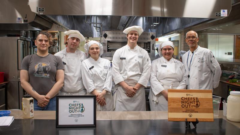 culinary students and their instructor, Chef Michael, smile and pose with their award in the Lane kitchen/classroom