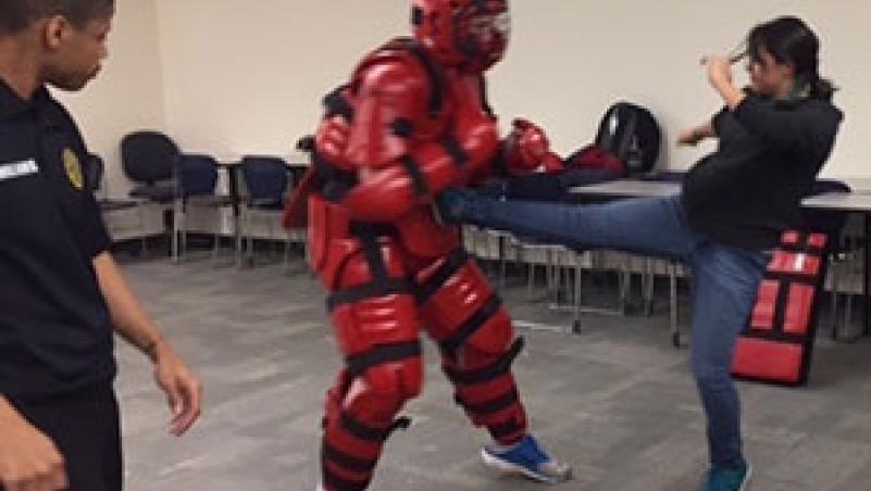 LCC Self-Defense Workshop image of woman kicking padded assailant