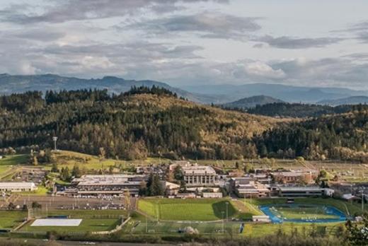 Overview shot of campus, from the hills to the North, showing a landsacpe of green with a distinct blue track
