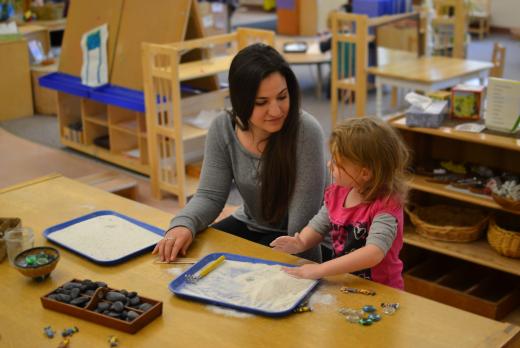 teacher and child playing with mini zen garden inside