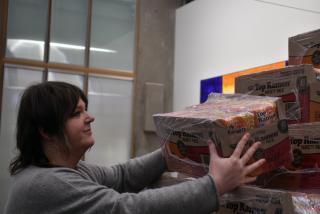 OER Librarian Meggie Wright places another case of ramen on the pyramid outside the library