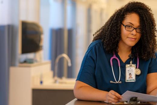 a medical assistant program student in scrubs filling out medical paperwork