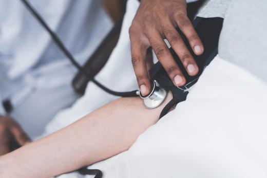 A BSN student uses a stethoscope and blood pressure cuff to measure a patient's blood pressure.