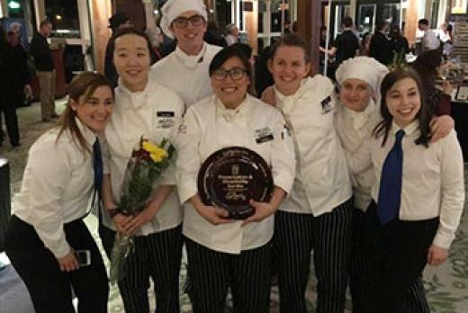 image of seven smiling culinary students with award and flowers