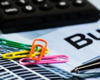 close up of a stack of papers with colorful paperclips, a pen, and a calculator on top