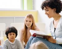 Teacher reading a book to a group of children