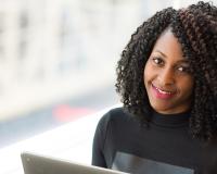 student with laptop smiling confidently 