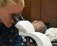 a geology student looks into a microscope