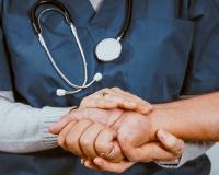 an RN program student holding a patient's hand
