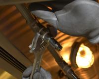 a plumber's gloved hands carefully tightening a nut around a pipe