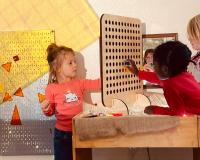 children playing with a pegboard as part of the early childhood education program
