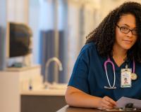 a medical assistant program student in scrubs filling out medical paperwork