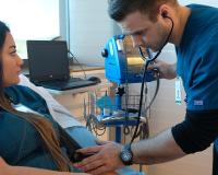 two bachelor of science in nursing students, one male and one female, practice taking blood pressure in the LCC nursing clinic