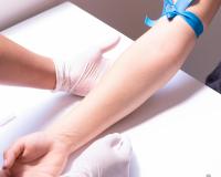 a patient resting their arm on a table as phlebotomist gets ready to draw blood