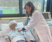 a student in a lab coat using medical technology in the Lane sim lab in her respiratory care class
