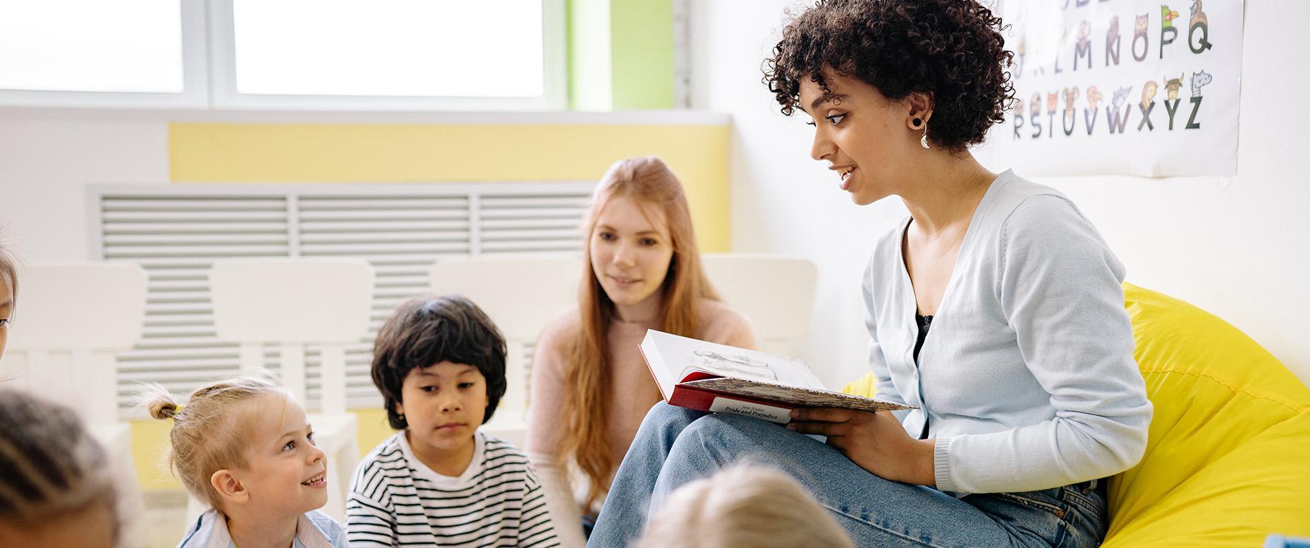 Teacher reading a book to a group of children