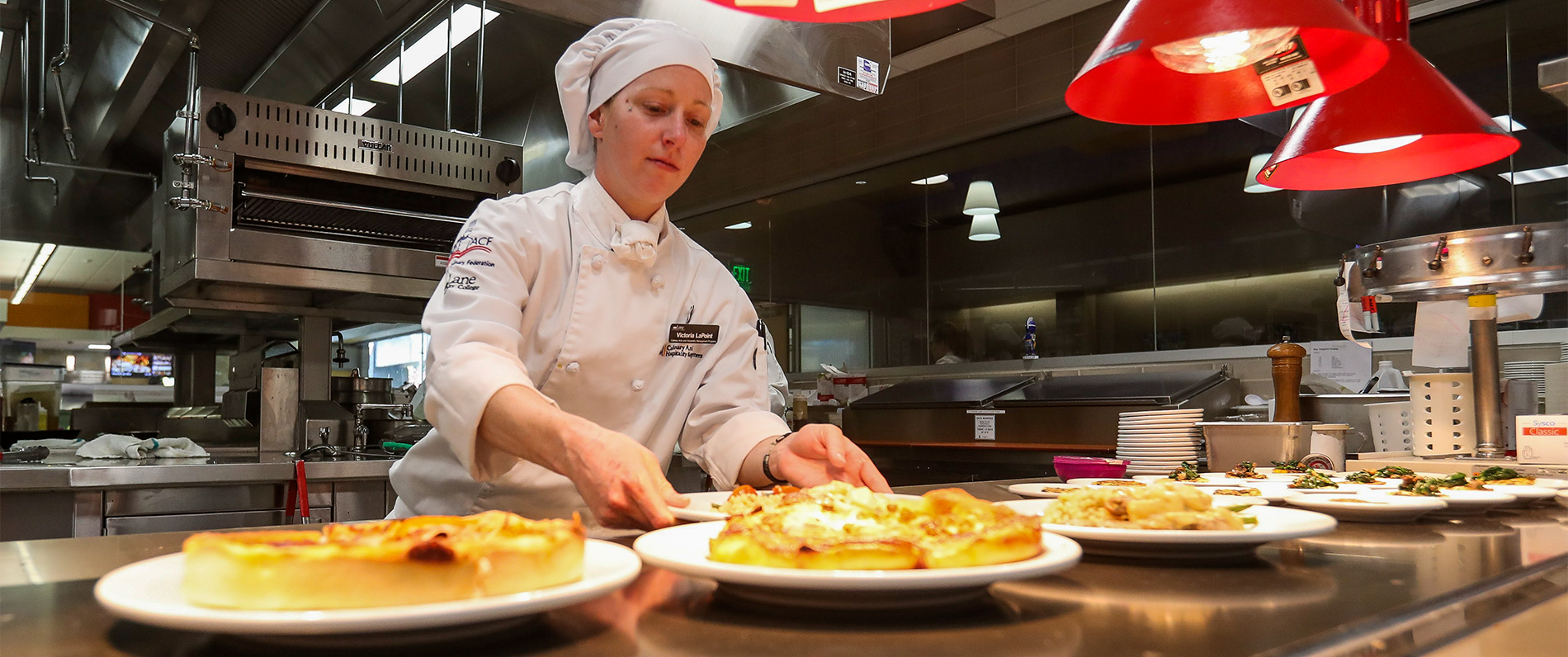 Culinary student placing plates ready for service