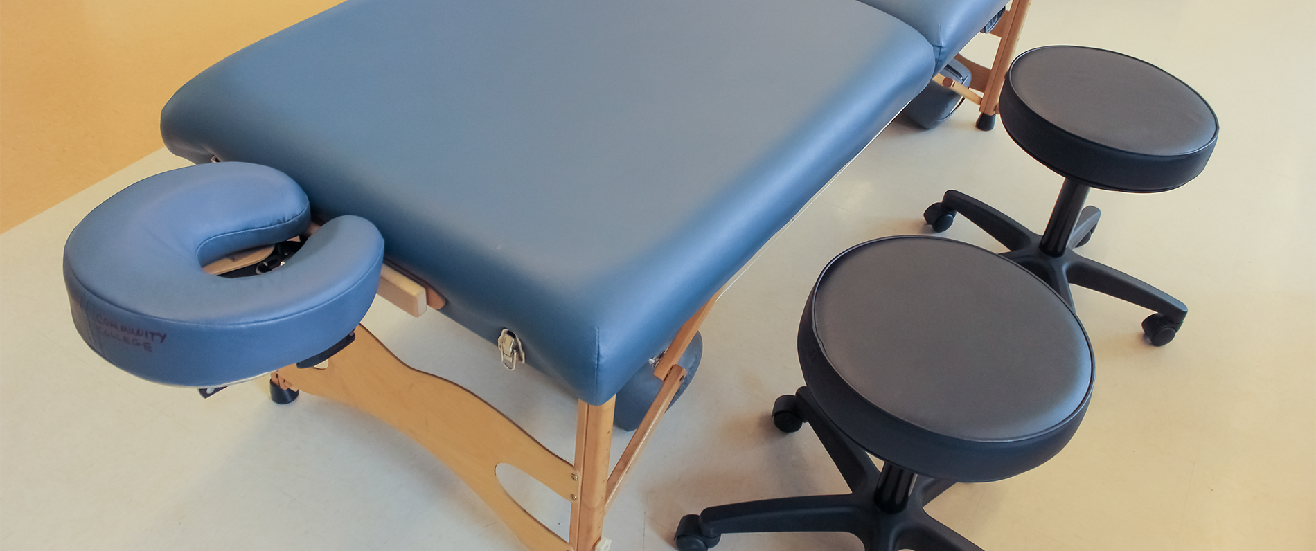 massage table and a stool at a massage school for a massage therapy program