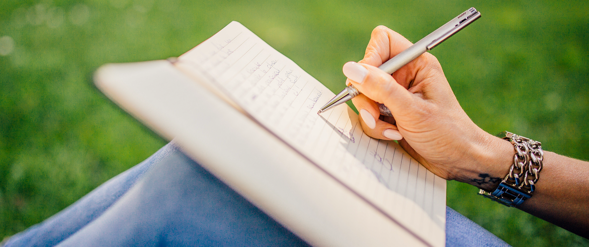 person writing on notepad propped up on their knees