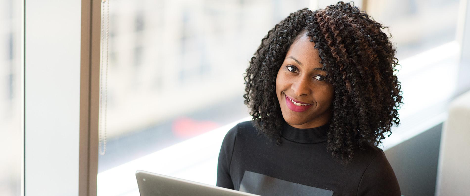 student with laptop smiling confidently 