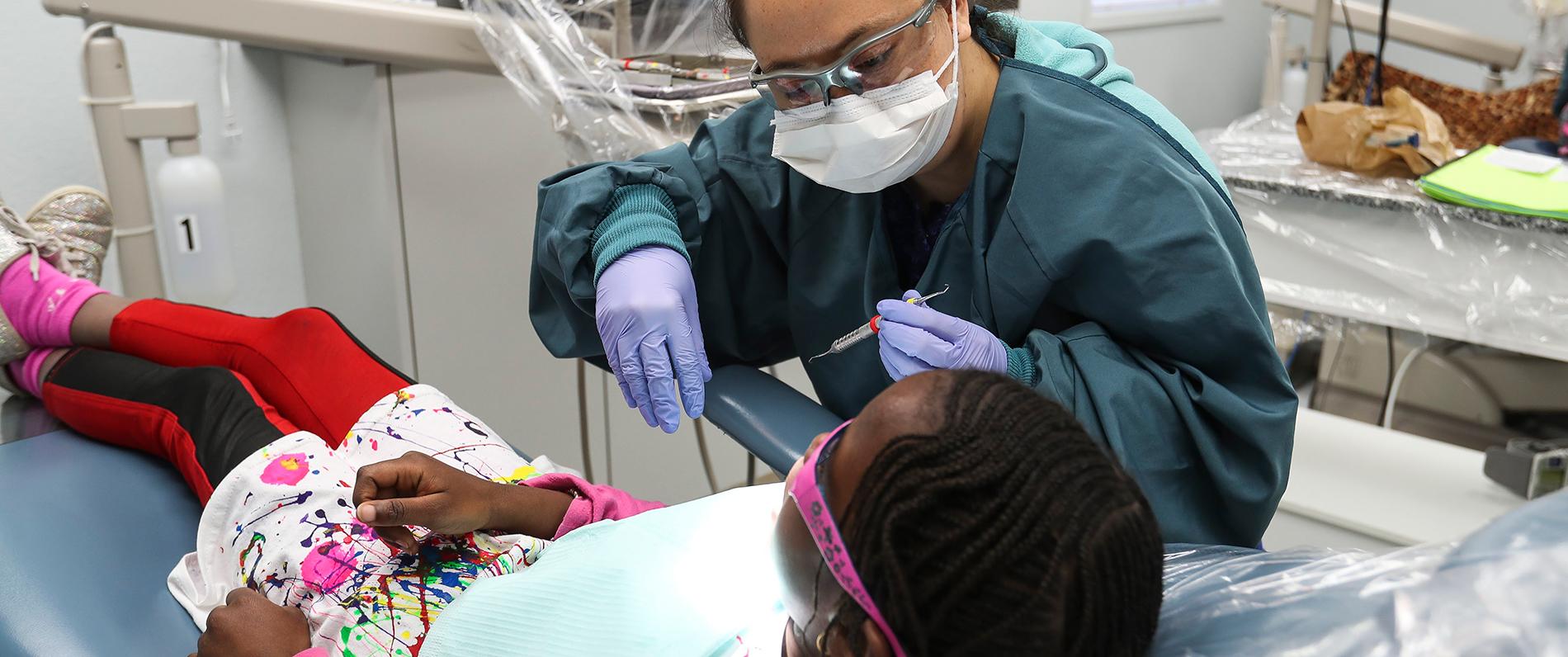 A student in LCC's dental assistant program works with a young patient