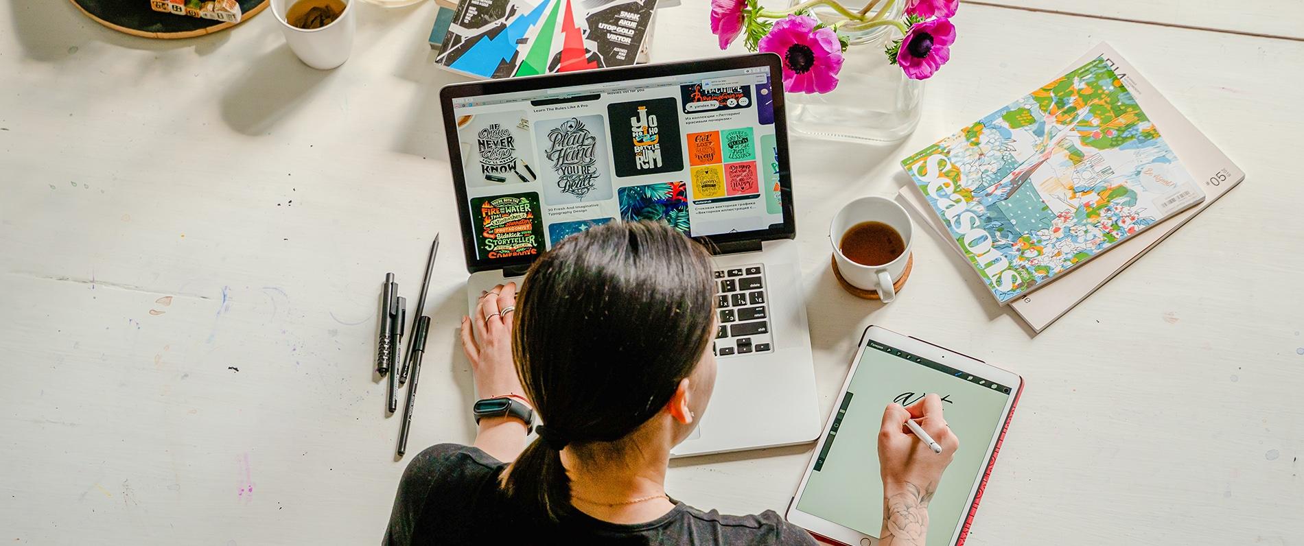 a graphic design program student gathering ideas for project using computer and sketch pad