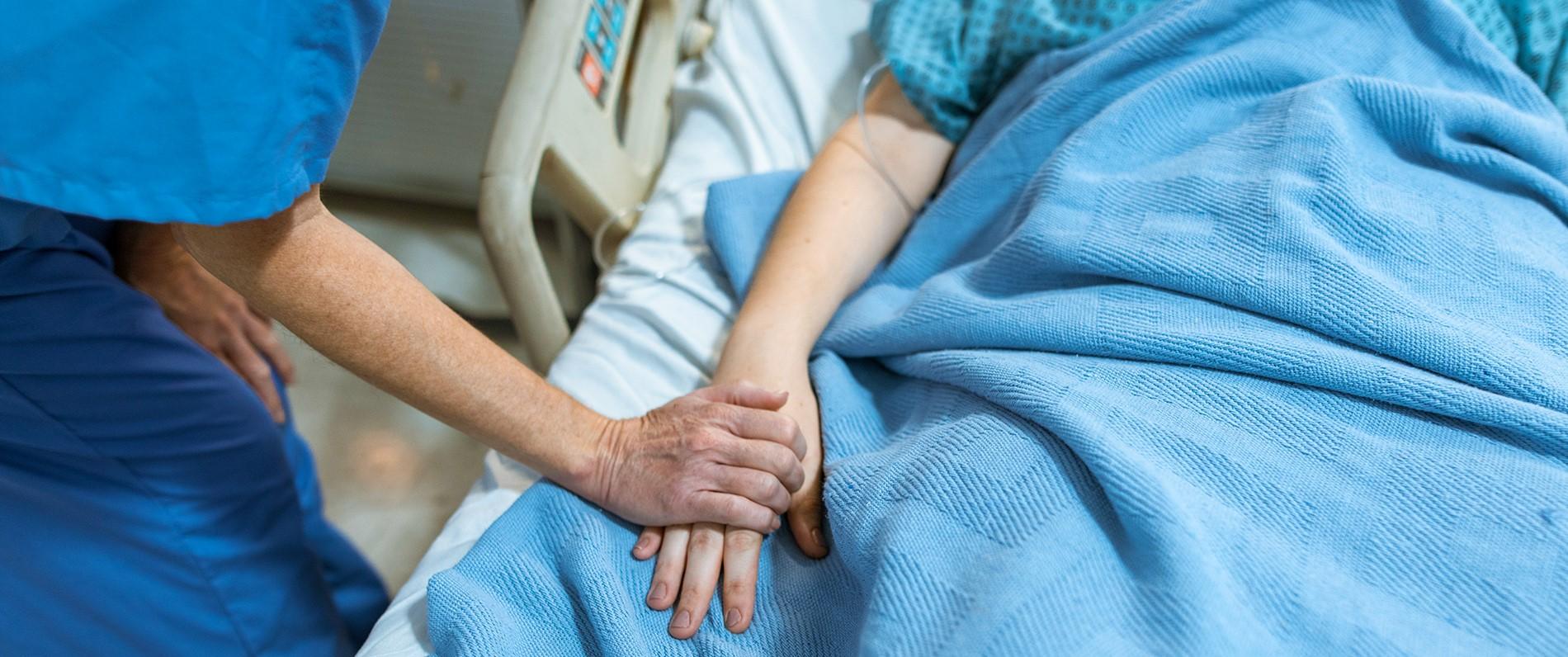 an LPN program student holding a patient's hand