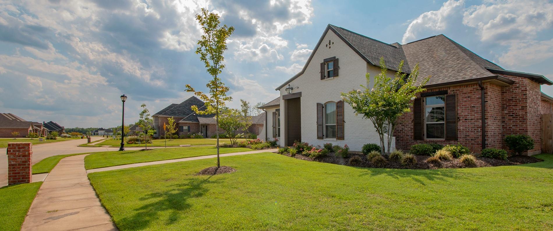 a lovely brick house with a big lawn on a sunny day