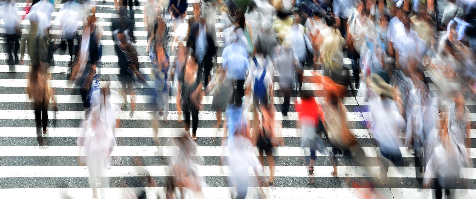 many people crossing a large crosswalk in a city