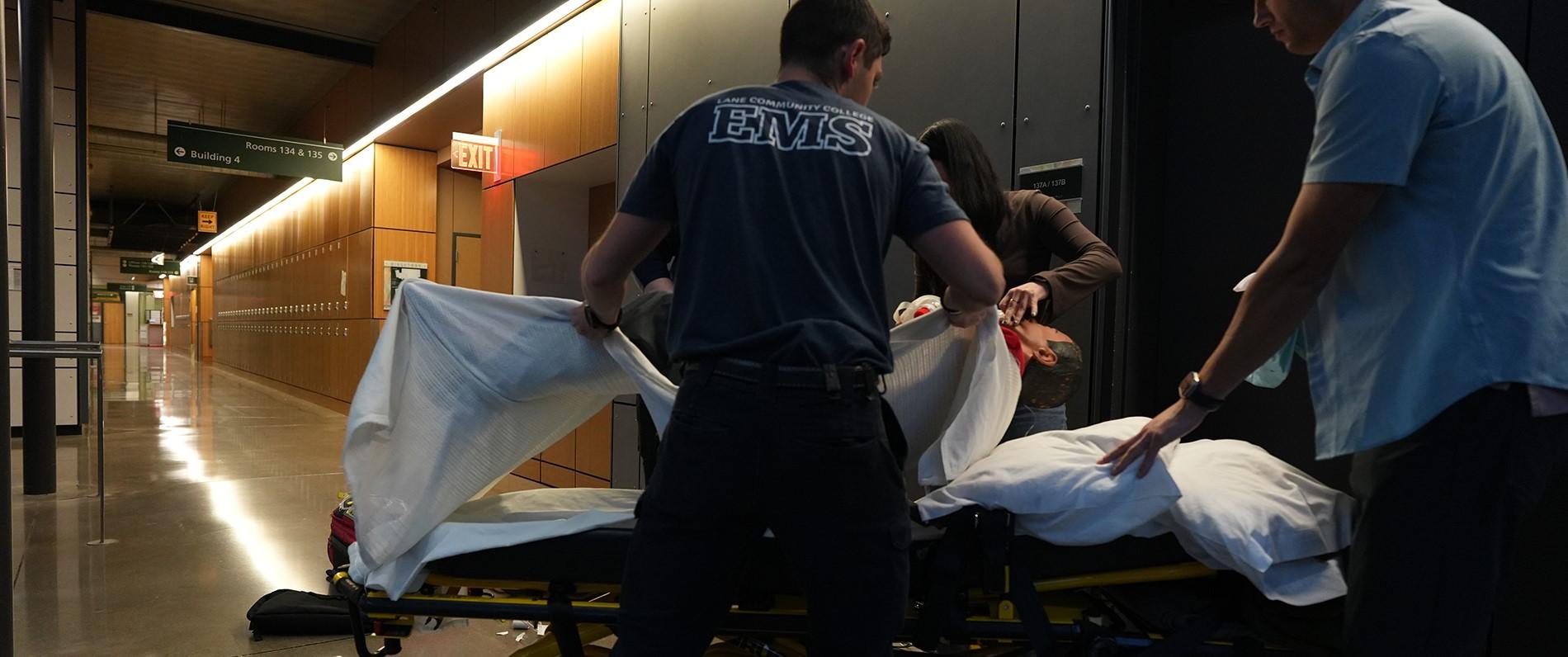 paramedicine students practice lifting a dummy onto a stretcher