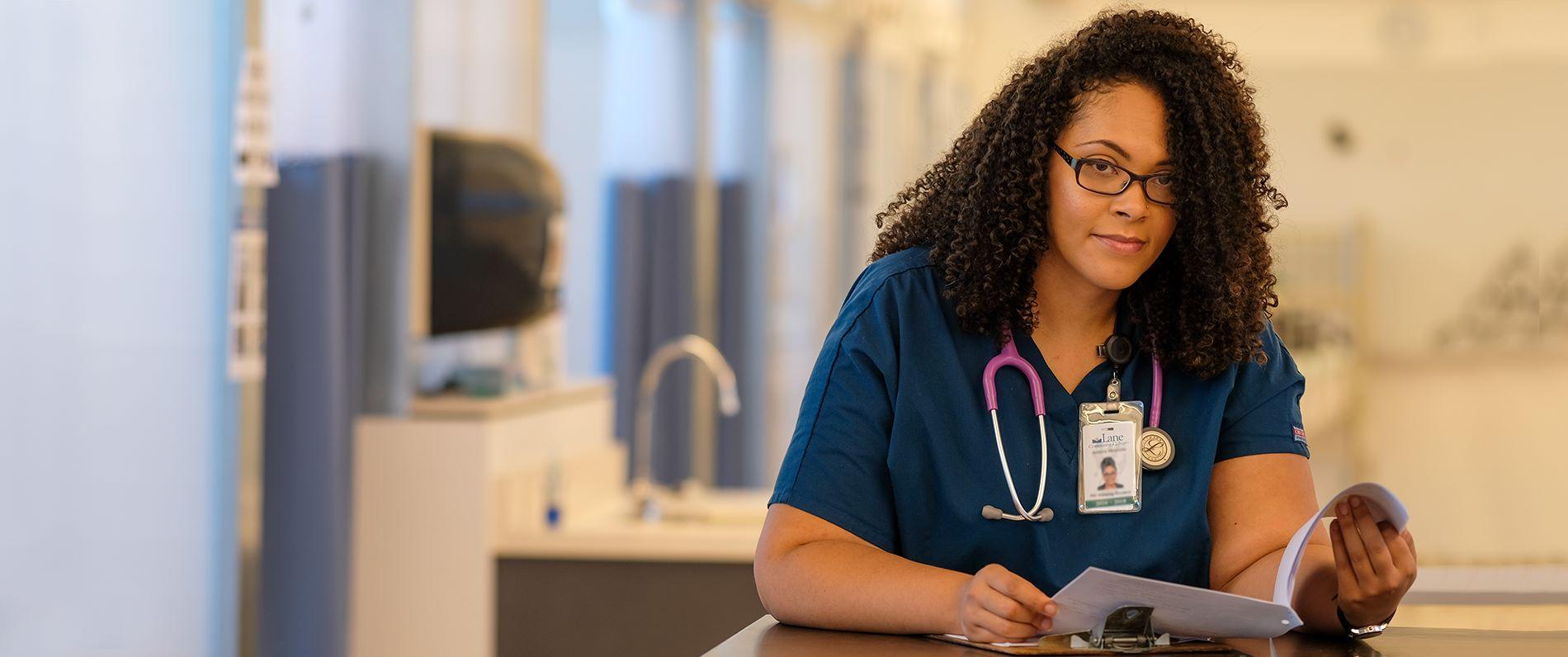 a medical assistant program student in scrubs filling out medical paperwork