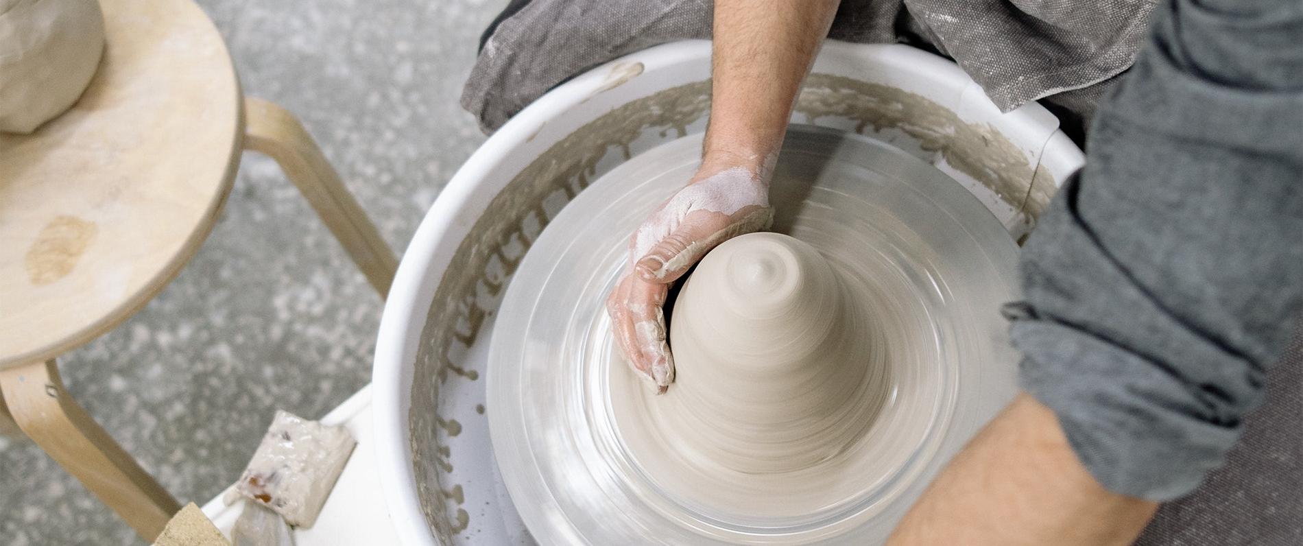 hands working clay on a pottery wheel