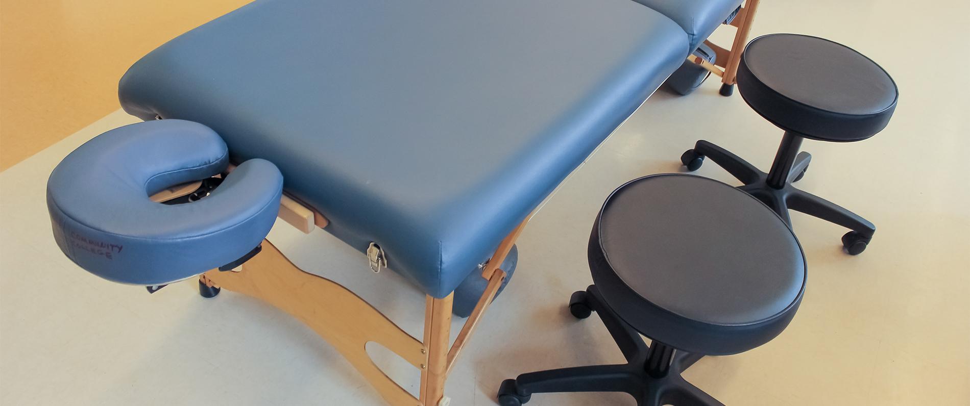 massage table and a stool at a massage school for a massage therapy program