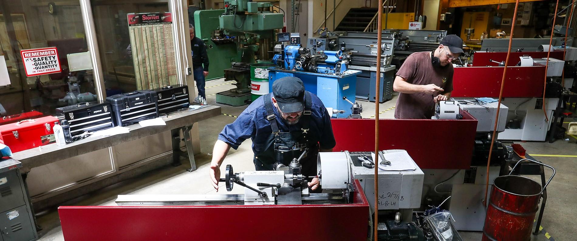 Millwrights and apprentices working in a shop with tools