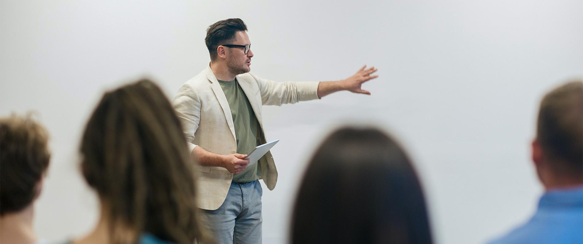A man in a blazer and trendy glasses gives a business presentation