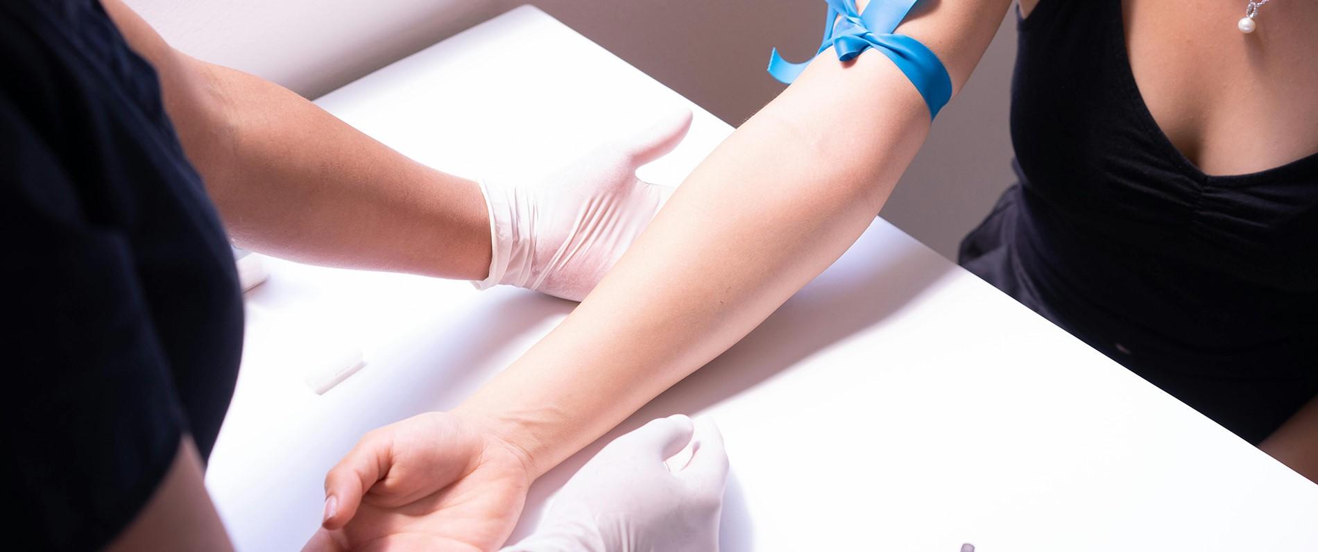 a patient resting their arm on a table as phlebotomist gets ready to draw blood