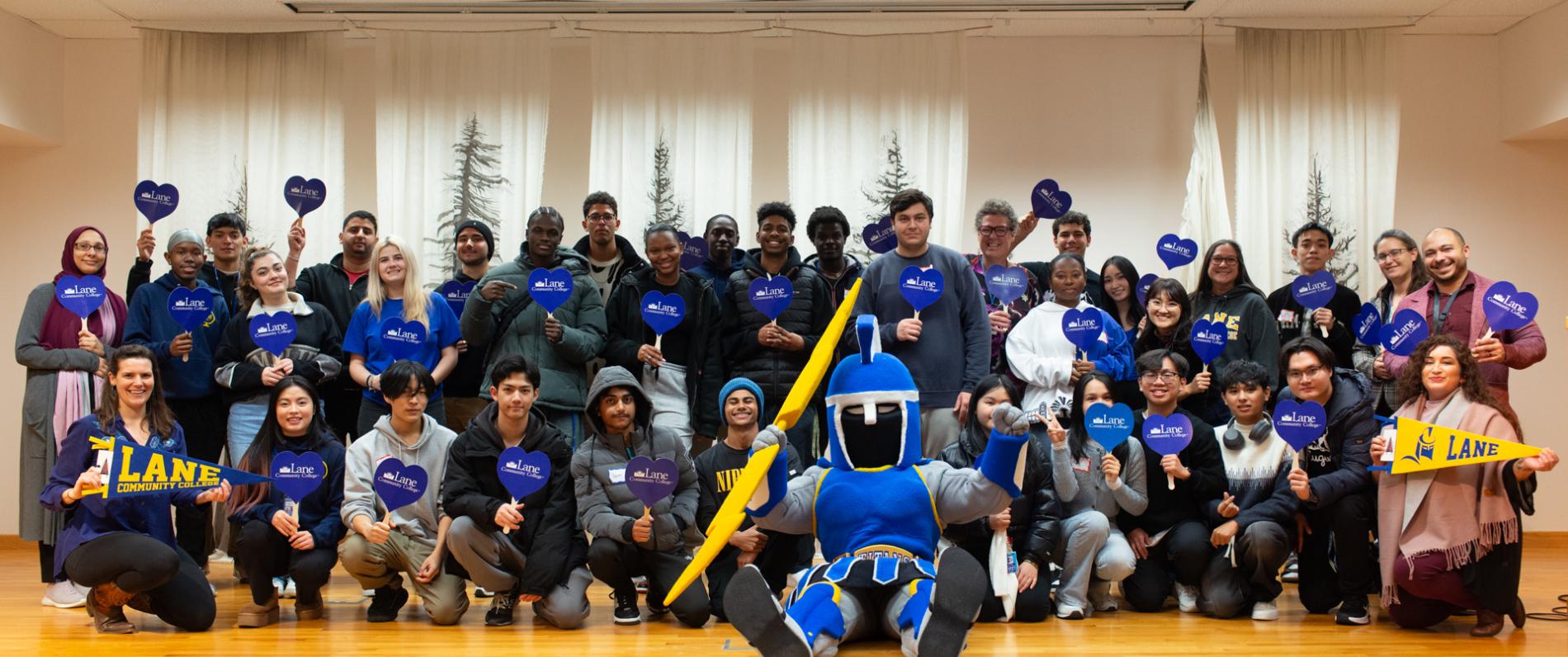 a group of about 35 international students and LCC staff pose at orientation with the Ty the Titan mascot
