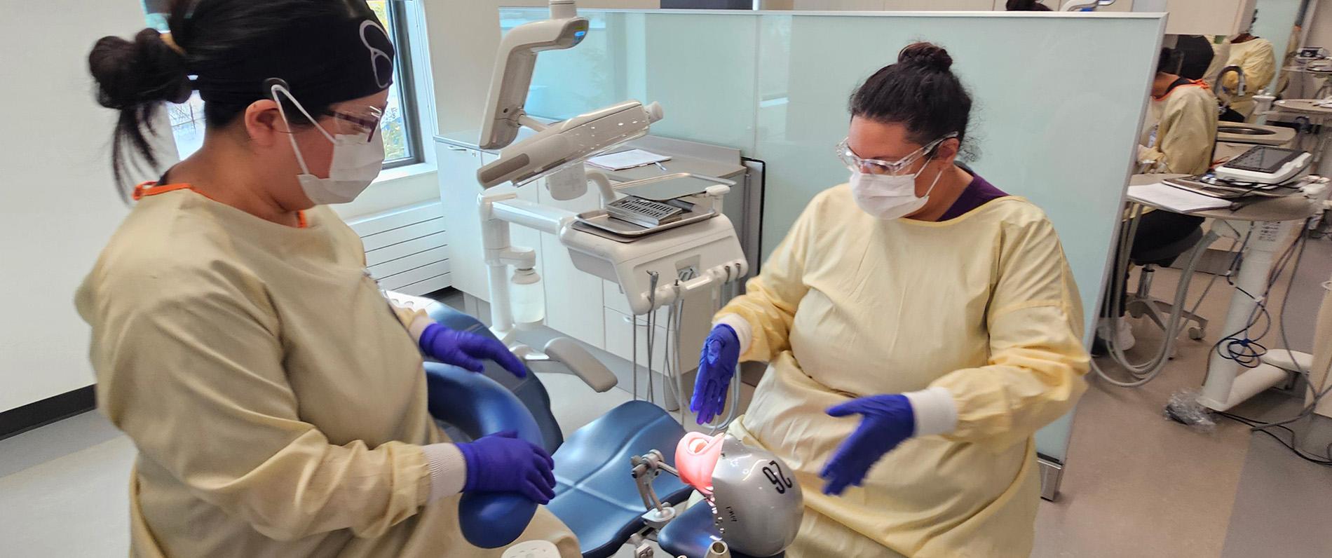 dental assisting students in scrubs and masks learn on a training dummy in the new LCC dental clinic