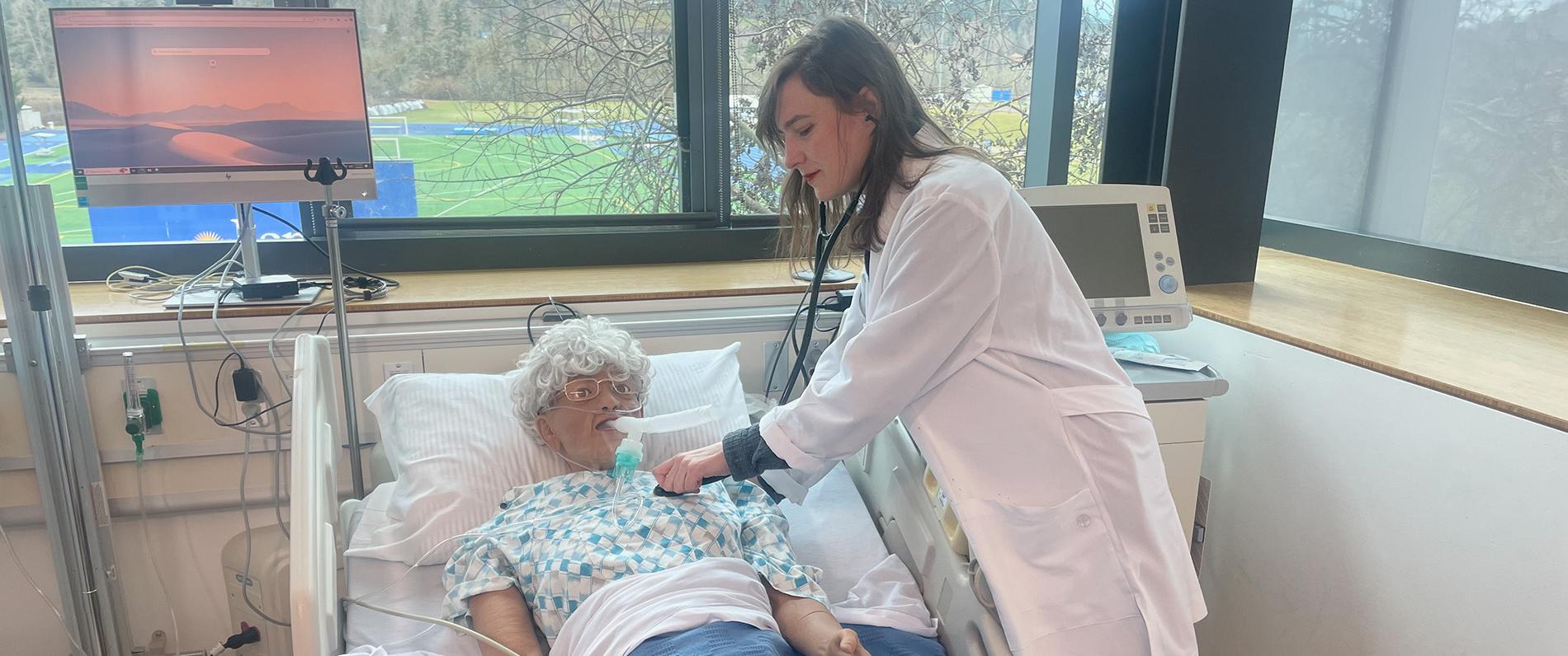 a student in a lab coat using medical technology in the Lane sim lab in her respiratory care class