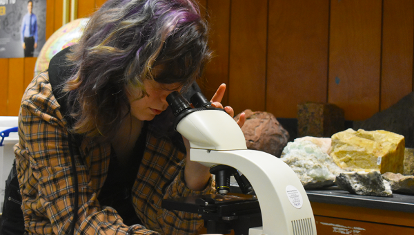 student in geology lab looking through microscope