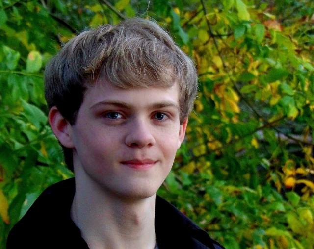 Nathan Matthews, an Early College and pre-med student, smiles with green foliage in background