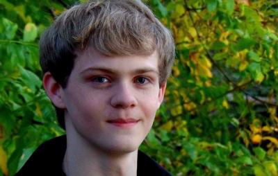Nathan Matthews, an Early College and pre-med student, smiles with green foliage in background