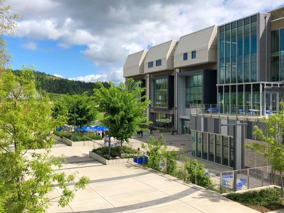 The center building on campus on a sunny day with bright green trees in the foreground