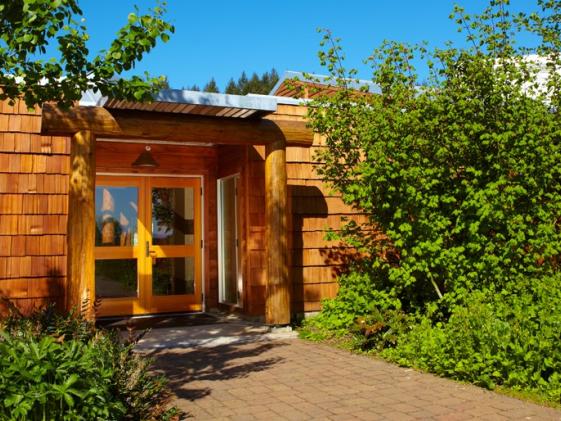 the entrance to the Longhouse at Lane with native plants and a bright blue sky