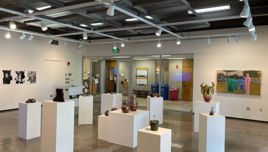 A bright art gallery room filled with student art of various mediums